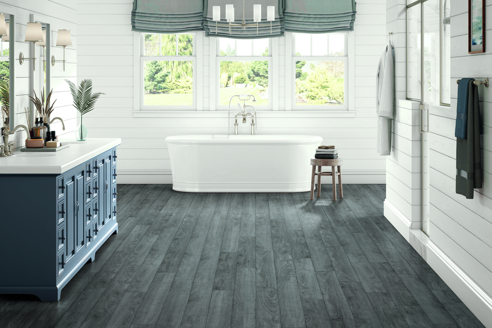 wood flooring in bathroom with soaker tub and window treatments with custom cabinets